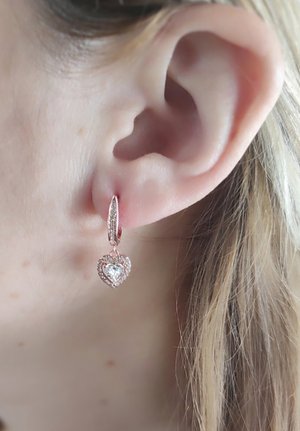 Ohrringe aus roségold mit Herzanhängern, verziert mit einem zentralen klaren Schmuckstein und kleineren umgebenden Steinen.