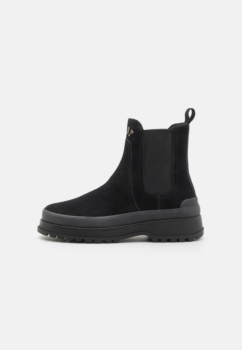 Black suede ankle boots with elastic side panels, a pull tab, and a thick black rubber sole featuring a rugged tread pattern.