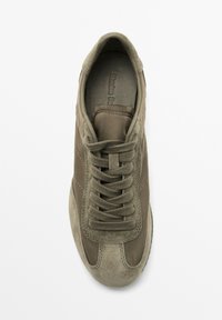 Sneaker verde oliva con una combinazione di suede e tessuto. Punta tonda, lacci piatti e dettagli cuciti lungo i lati.