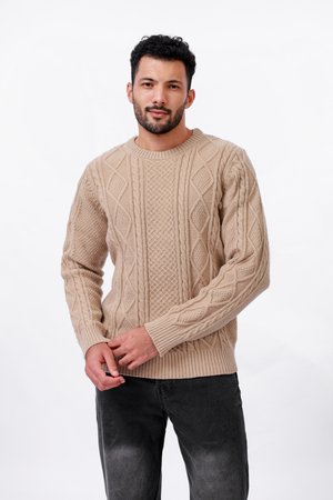 Beige cable-knit trui met een ronde halslijn en geribde manchetten, met diamanten en textuurpatronen door het hele kledingstuk. Gecombineerd met donkergrijze jeans.