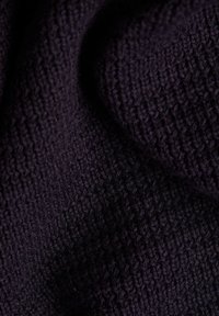 Gros plan d'un tissu tricoté violet foncé avec un tissage texturé visible et des plis doux.