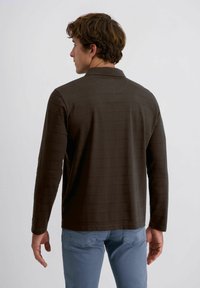 Braunes Langarmshirt mit einem dezenten gestreiften Muster, klassischem Kragen und entspannter Passform, kombiniert mit hellblauen Jeans.