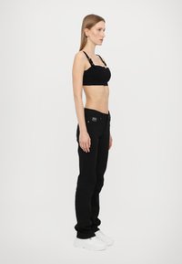 Black cropped top with adjustable straps, textured fabric; paired with black skinny jeans and white sneakers. Simple and sleek silhouette.
