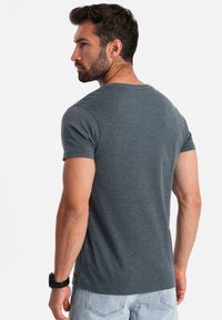 Grå kortärmad t-shirt med rund halsringning, som visar en mjuk tygtextur. Designad med en åtsittande siluett och minimala sömmar.