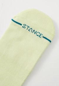 Calzino a crew giallo chiaro realizzato in misto cotone, con una lavorazione a maglia testurizzata e un logo "STANCE" turchese ricamato vicino al polsino.