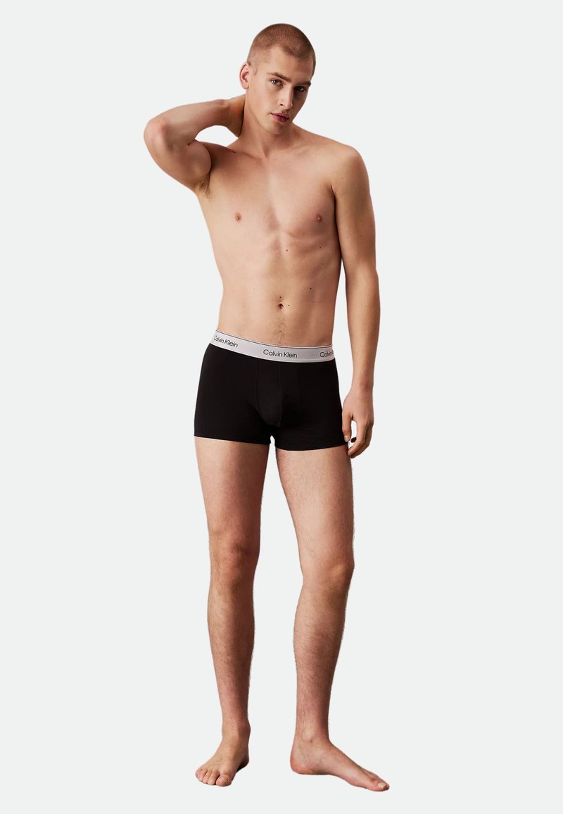 Black cotton boxer briefs with a white elastic waistband featuring "Calvin Klein" branding. Smooth texture, fitted design, and short legs.