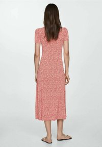 Robe midi florale rouge avec des manches courtes à volants, corsage ajusté et jupe évasée. Tissu lisse, motif subtil et silhouette féminine.