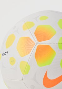 Μπάλα ποδοσφαίρου Nike Pitch, λευκή με εξαγωνικά μοτίβα σε κίτρινο, πράσινο και πορτοκαλί, λεία υφή και εμφανείς λεπτομέρειες ραφής.