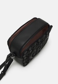 Borsa nera con finitura texturizzata e accenti in pelle liscia. Presenta scomparti con doppia zip e una forma rettangolare compatta.