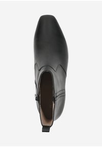 Bottine en cuir noir avec un bout pointu, fermeture éclair latérale et détails cousus sur le dessus. Texture lisse et design minimaliste.