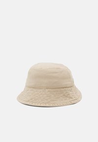 Beige cotton bucket hat with a textured finish, rounded crown, and wide, downward-sloping brim. No visible logos or hardware details.