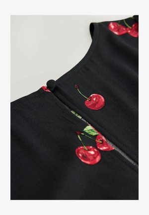 Črna bluzica z vezenimi rdečimi češnjami in zelenimi listi, z izrezom v obliki ključavnice in detajlom gumbne zap closure.