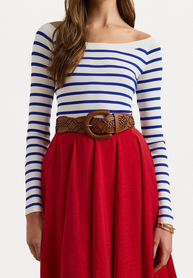 Haut à manches longues rayé bleu et blanc, associé à une jupe rouge et une ceinture tressée marron. La texture du tissu semble lisse.