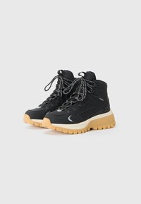 Czarne sneakersy za kostkę z teksturowanej tkaniny, wzmocnionymi oczkami i kontrastującą gumową podeszwą. Posiadają grube sznurówki i dekoracyjne przeszycia.
