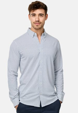 Weißes Hemd mit blauen Punkten, lange Ärmel und klassischem Kragen. Der Stoff wirkt glatt und hat einen taillierten Schnitt.