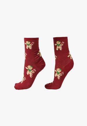 Chaussettes rouges pour cheville avec motifs répétés de bonhommes en pain d'épice tenant une canne en sucre d'orge, placées côte à côte sur un fond blanc.