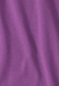Gros plan sur un tissu tricoté violet doux montrant une texture fine et des plis délicats.