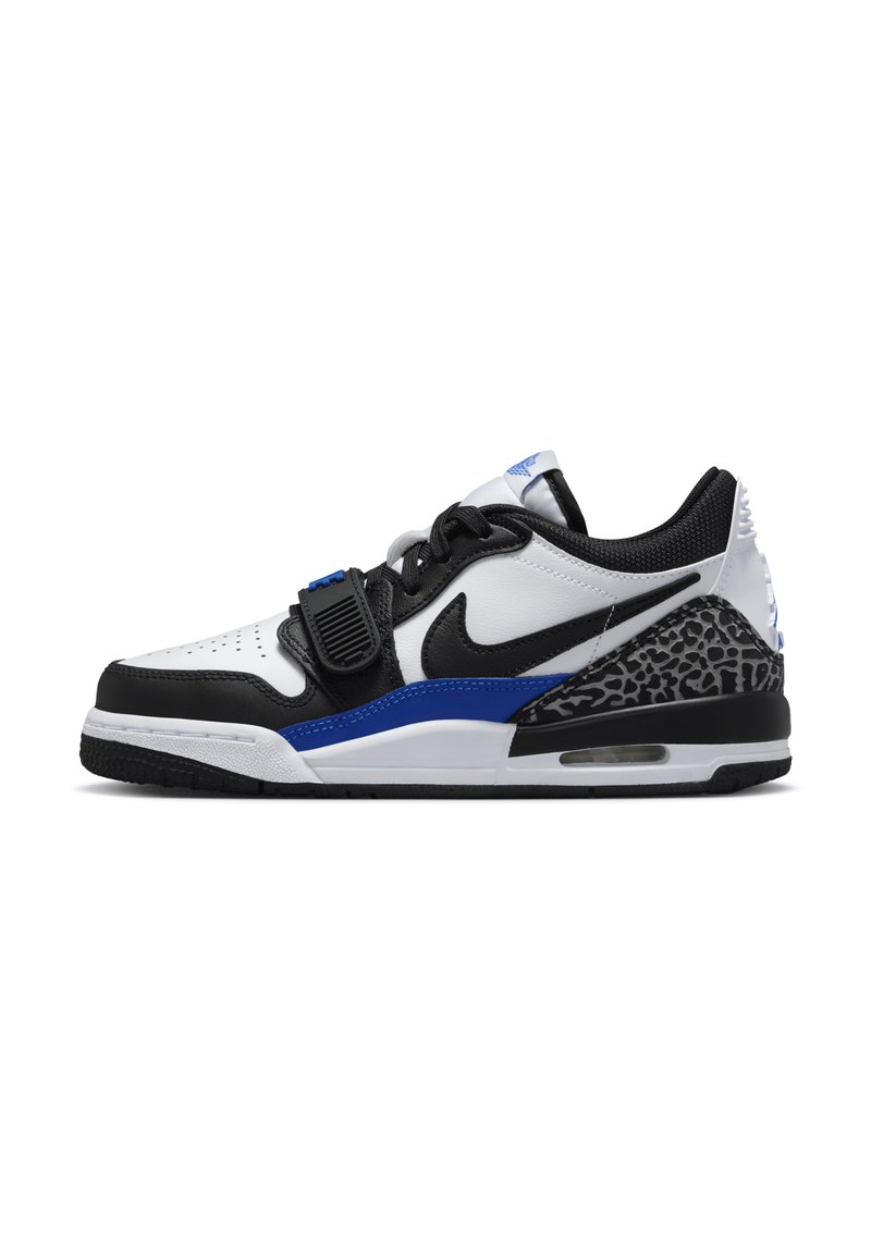 A Nike sneaker fehér bőr felsőrésszel rendelkezik, fekete és királykék kiegészítőkkel, texturált szürke középtalppal, és látható légpárnával.