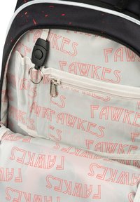 Černý batoh má vnitřek s bílou podšívkou s opakujícím se červeným textem "FAWKES". Obsahuje zipovou kapsu a organizační přihrádky.