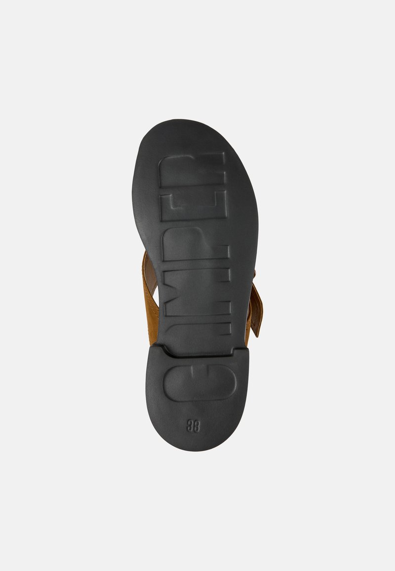 Sandalia de cuero marrón con una suela de goma negra. La suela presenta el texto 'CAMPEL' en letras elevadas y un tacón redondeado y liso.