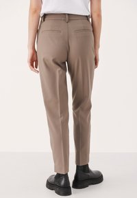 Beige skräddarsydda byxor med en insvängd passform, som har två bakfickor och ett slätt tyg. Matchat med svarta ankelstövlar.