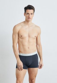 Tengeréskék boxer short, puha anyagból készült, szürke Nike logóval ellátott derékpánttal. A kialakítása klasszikus formájú és mérsékelt rugalmasságú.