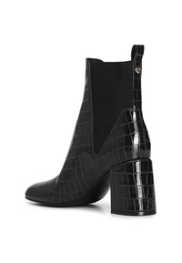 Botine negre la gleznă cu o textură lucioasă de crocodil, panel lateral elastic și toc pătrat. Dispune de un mâner la spate pentru a fi ușor de purtat.