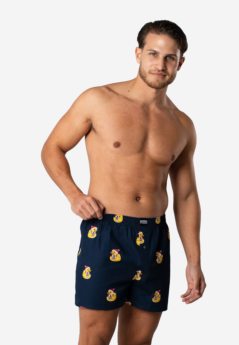 Marineblauwe boxers met een herhaald patroon van gele rubberen eenden in kerstmannenkappen. Gemaakt van lichtgewicht stof, met een elastische tailleband voor comfort.