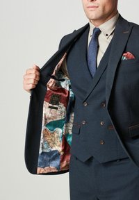 Granatowa marynarka w stylu dwurzędowym, z kolorowym podszewką w mapy i dwoma brązowymi guzikami z przodu.