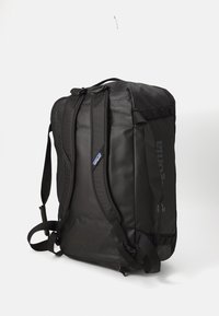 Black rectangular backpack with padded shoulder straps, side handle, and Patagonia logo on the side, shown against white background.