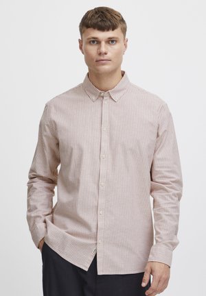 Camisa de manga larga con botones que presenta un patrón de rayas rosa claro y blanco, cuello y bajo curvado. La tela parece suave y texturizada.