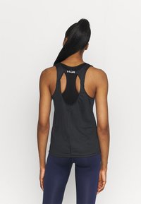 Černý sportovní nátělník s designem s průstřihy na závodnickém zádech, vyrobený z lehké látky, s logem na horní části zad.