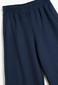 Navyblaue gerippte Hose mit einem elastischen Bund und einer weichen Textur. Das Design weist vertikale Streifen für ein dezentes Muster auf.