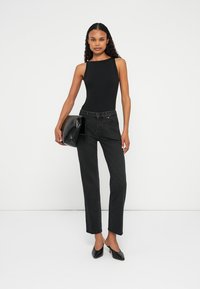 Must have mustriba bodysuit, kõrge kaelusega; kõrge vöökohaga mustad teksad; ülisuur must rahaasja; terava ninaga mustad kontsad; minimalistlik disain.