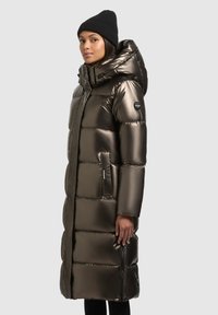 Lang pufferjas in metallic donkergroen, met een capuchon, geborduurd ontwerp, zijzakken en een zwarte gebreide muts. Glad, glanzend oppervlak.