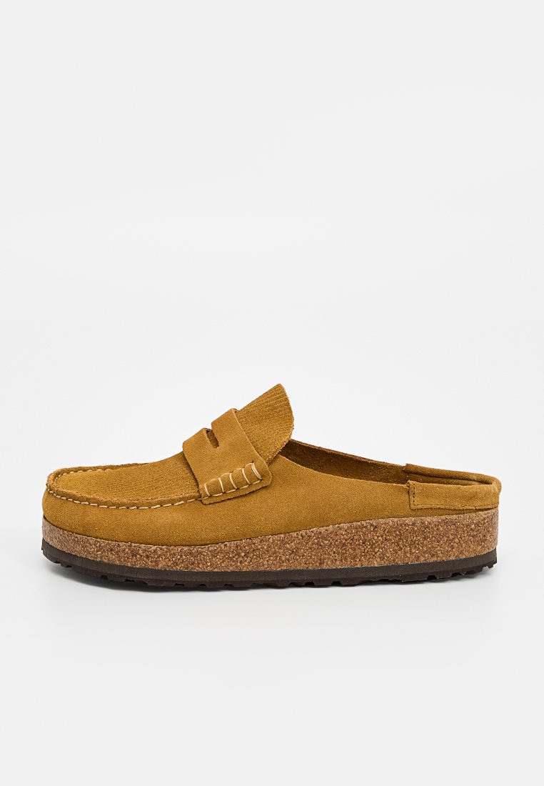 Mules en suède beige pour hommes, à enfiler, avec des coutures de style mocassin et une semelle en liège, présentées en profil sur un fond blanc.