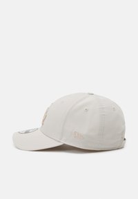 Beige Kappe mit gebogenem Schild, mit gesticktem Logo auf der Vorder- und Seitenfläche, aus glattem Stoff und mit Belüftungsösen.