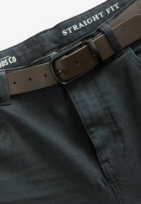 Pantalones de corte recto de color azul oscuro con una textura suave, que presentan un cinturón de cuero marrón con una hebilla negra y detalles de costura visibles.