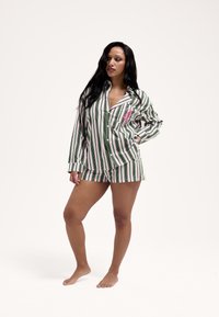 Zöld és rózsaszín csíkos pizsamaszett, amely gombos hosszú ujjú felsőt és hozzá illő rövidnadrágot tartalmaz. Pamut anyagból készült, puha tapintású.