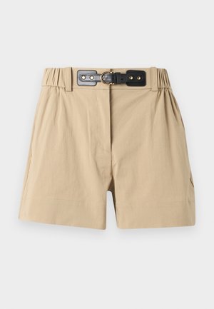 Shorts beige taille haute avec côtés élastiques et ceinture noire ornée d'une boucle dorée, présentés sur un fond uni.