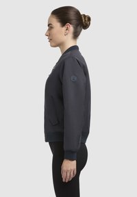 Merineelne pommik jacket, millel on lukuga eesmine osa, soonikust käised ja plaastriga vasakul varrukal. Omab küljetaskut ja sileda tekstuuri.