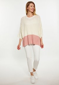 Maglione leggero a maglia in gradiente avorio e rosa, con una vestibilità ampia e maniche larghe, abbinato a pantaloni bianchi e sneakers.