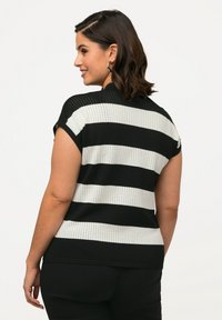 Maglione a righe bianche e nere con maniche corte, caratterizzato da un tessuto testurizzato e orlo arrotondato, visto da dietro.