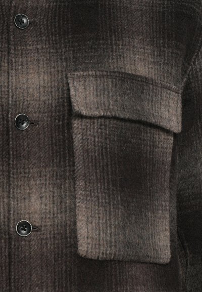 Brown plaid shirt jacket in a soft wool blend, featuring a flap pocket, round black buttons, and a textured finish.