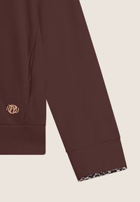 Sweatshirt bordeaux avec une texture lisse, présentant un accent logo doré et un doublage à imprimé léopard au niveau des poignets.