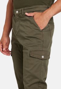 Pantaloni cargo verde oliva realizzati in tessuto resistente, con tasche laterali dotate di patte e chiusure a scatto in metallo, e una vestibilità comoda.