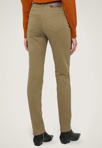 Beige, slim-fit broeken met een gladde textuur, met twee achterzakken en een leren label. Gepaard met zwarte enkellaarsjes.