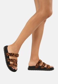 Sandali con stampa leopardata marrone, dotati di due cinturini regolabili, tomaia in tessuto morbido e suola in gomma nera, mostrano un design open-toe.