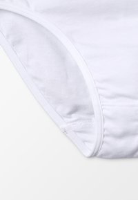 Culotte blanche en coton présentant une texture lisse, une taille élastique et une coupe arrondie le long des ouvertures des jambes avec des détails de couture soignés.