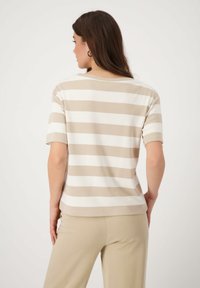 Beige and white striped short-sleeve top with a round neckline, featuring a soft, smooth texture, paired with light-colored pants.